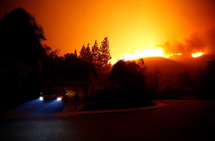 A resident looks at approaching flames as firefighters battle flames overnight during a wildfire that burned dozens of homes in Thousand Oaks