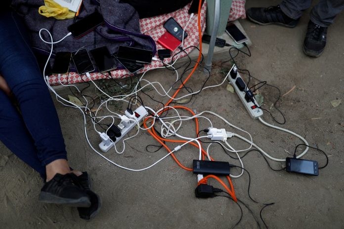 Migrants, part of a caravan traveling en route to the United States, charge their cellphones as they stay in a sport center that is currently used as a temporary shelter in Tijuana