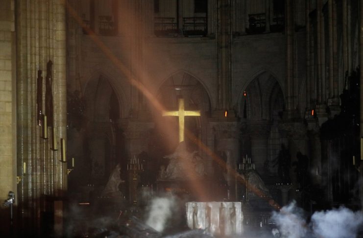 Smoke rises around the altar in front of the cross inside the Notre Dame Cathedral as a fire continues to burn in Paris
